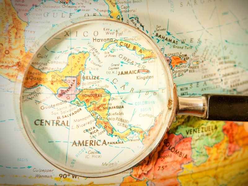 Lupa sobre un mapa de Centroamérica para representar rutas logísticas y flujo de abasto de alimentos.